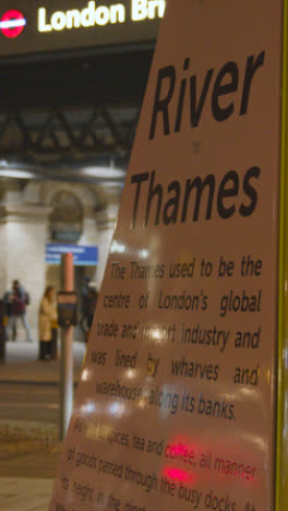 Vertikales-Video,-Das-Den-Eingang-Zum-Bahnhof-London-Bridge-Mit-Touristischen-Informationen-Bei-Nacht-Zeigt